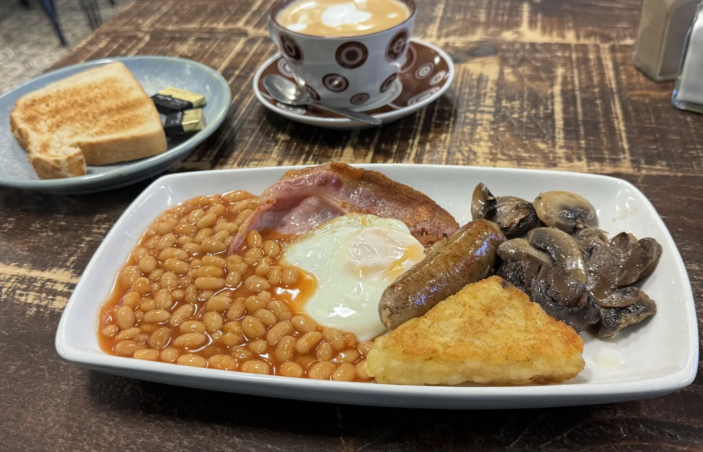 A Cafe Latte breakfast with eggs, beans, sausage, mushrooms and toast