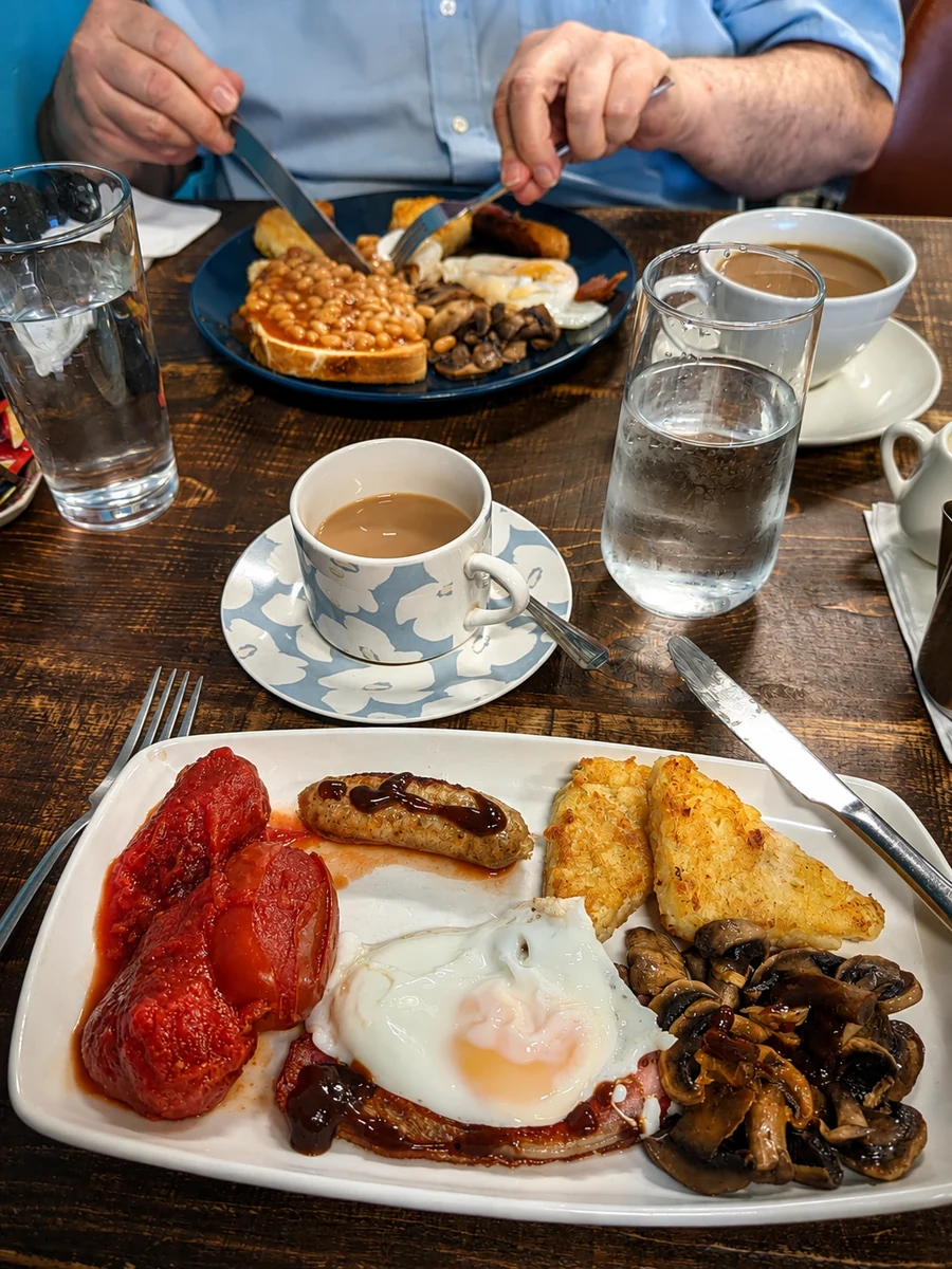 A cooked breakfast with eggs, mushrooms, tomatoes and hash browns